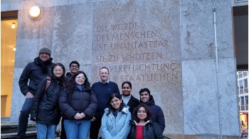 Die Gruppe von 9 Personen vor dem in Stein gemeißelten Schriftzug: "Die Würde des Menschen ist unantastbar. Sie zu schützen ist Verpflichtung aller staatlichen Gewalt", der sich am Landgericht Braunschweig findet.