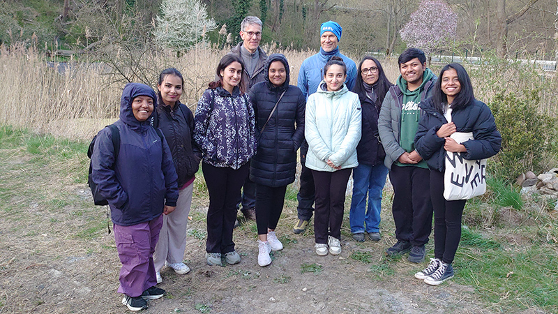 Dr. Martin Erbs and Jörg Platzer together with the DAAD students on a meadow, with a forest visible in the background.