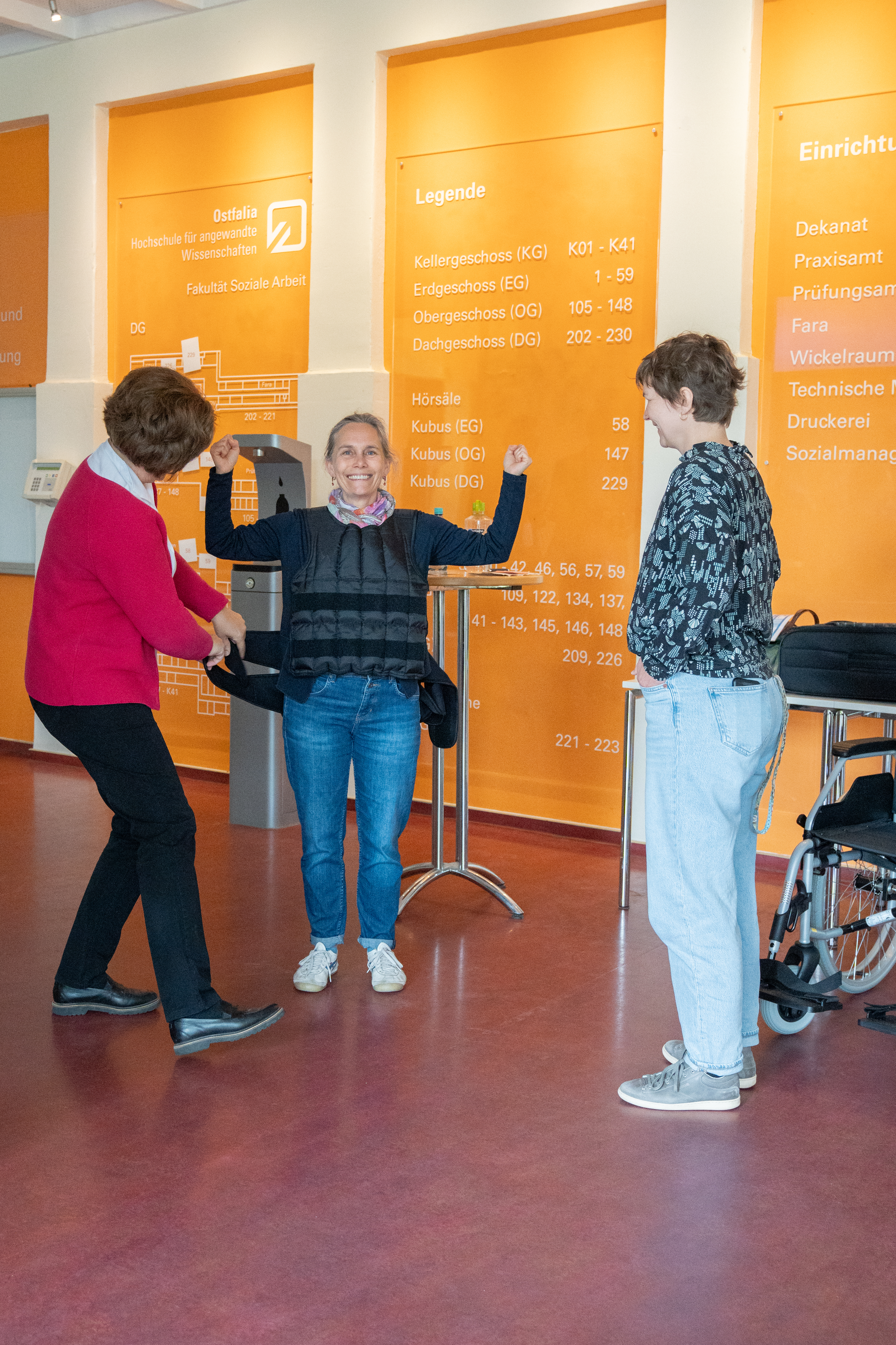 Eine Teilnehmerin simuliert mit einer schweren Weste die Bewegungseinschränkungen älterer Menschen