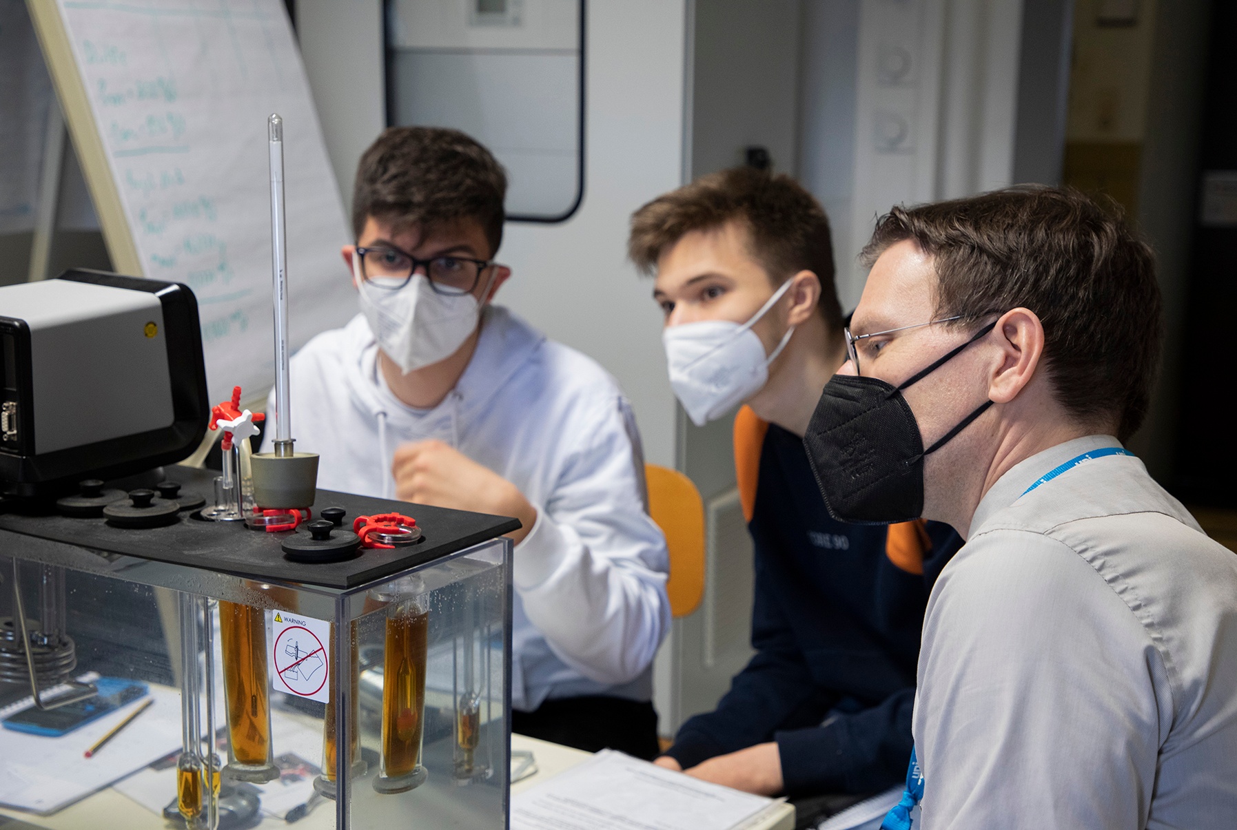 Prof. Henning Zindler (re.) und zwei Schüler beim Versuch am Kapillarviskosimeter.