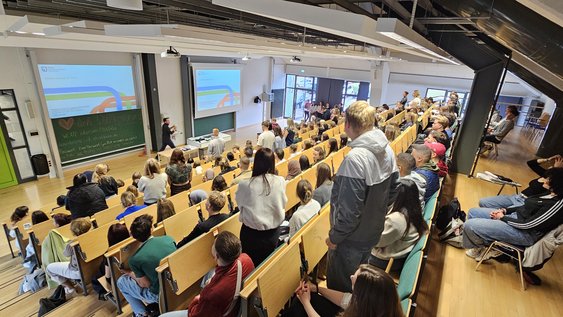 Der Hörsaal Am Exer 11 gefüllt mit Erstsemestern mit Blick auf die Tafel an der Helge Keller alle Anwesenden begrüßt.